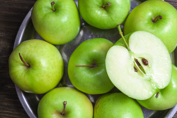 ripe green apples and apple slices on wooden gray background