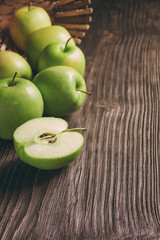 ripe green apples and apple slices on wooden gray background