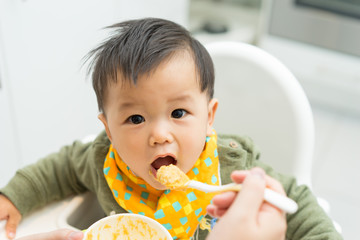 Asian baby boy eating blend food on a high chair - 134897673