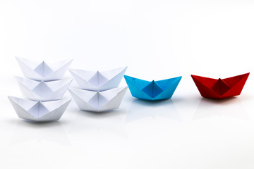 Leadership concept with red paper ship leading among white