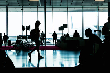 Silhouette of young woman going in waiting hall.