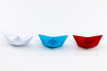 Leadership concept with red paper ship leading among white