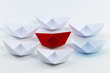 Leadership concept with red paper ship leading among white