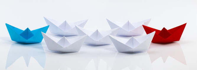 Leadership concept with red paper ship leading among white