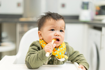 Asian baby boy eating blend food on a high chair