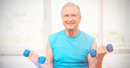 Fototapeta na wymiar Portrait of senior man exercising with dumbbells