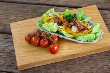 Vegetable salad and cherry tomatoes on wooden board 