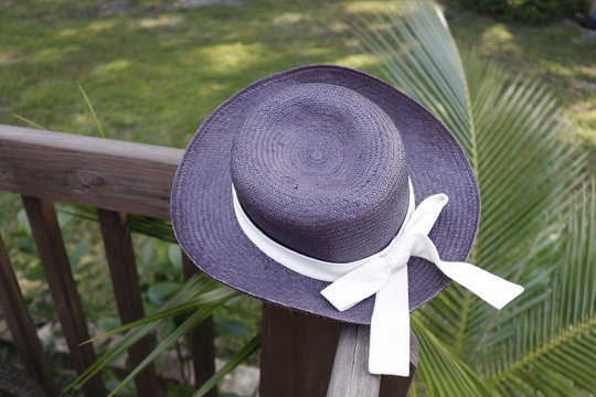 Straw hat with baw on wooden fance