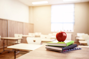 School teacher's desk with stack of books and apple