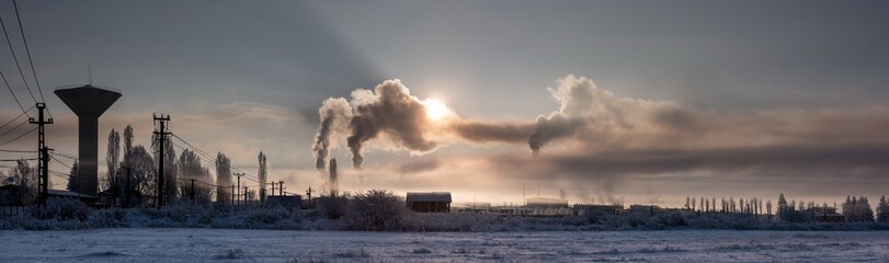 Polluting the atmosphere. It is very cold in the morning sunrise industrial landscape.