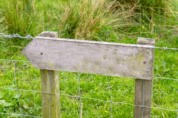 Blank Directional Wooden Sign on a Fence with Grass in Background