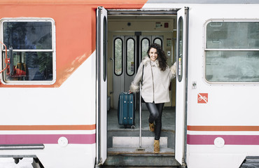 Girl with suitcase that goes down the coach of the train