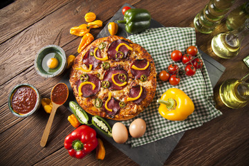 Tasty pizza, tomatoes and others ingredients on a wooden backgro