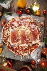 Tasty pizza, tomatoes and others ingredients on a wooden backgro