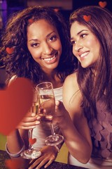 Composite image of happy young women having champagne