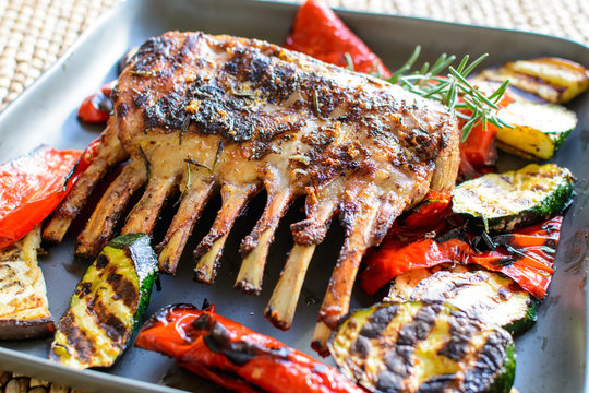 Grilled rack of lamb chops with grilled vegetables and rosemary on a sunny day.