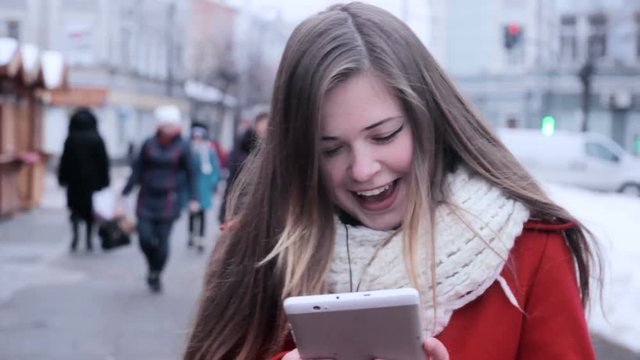 Moon-faced girl walks at street and watching tablet pc