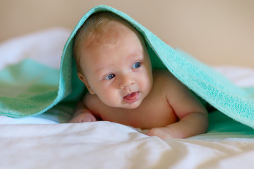 little child baby under a towel posing and smiling