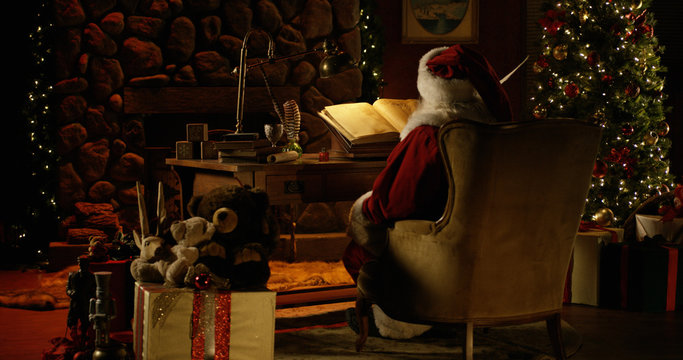 Santa Claus works at his desk, surrounded by Christmas decorations