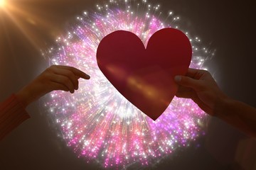 Composite image of couple holding a heart