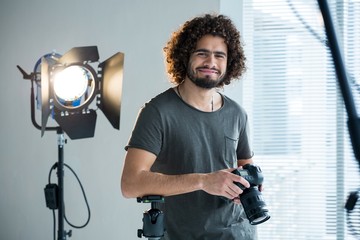 Happy male photographer standing in studio - obrazy, fototapety, plakaty