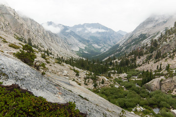 Fototapeta na wymiar Towering granite peaks rise above a deep forested alpine valley in California's high sierra