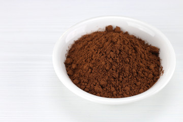 Cocoa powder in white bowl over wooden background