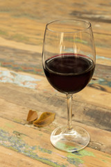 Glass of red wine with autumn leaves on wooden table