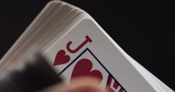 Person flips through deck of playing cards, close up