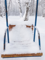 Swings covered with snow in the forest