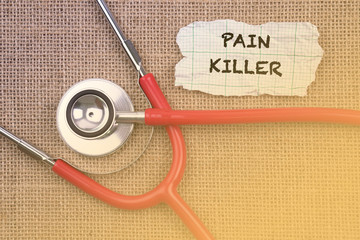 Stethoscope, paper with word “ PAIN.  KILLER “. Medical Concept