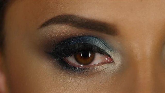 Girl with an evening make up closes and opens the eyes. Close up. Slow motion