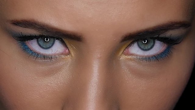 Girl looks fierce and terrible gaze upwards. Close up. Black background. Slow motion