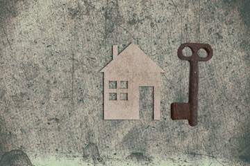 model of cardboard house with key on old textured paper backgrou