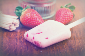 Homemade strawberry ice lolly on rustic background