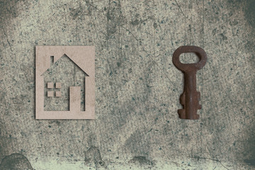 model of cardboard house with key on old textured paper backgrou