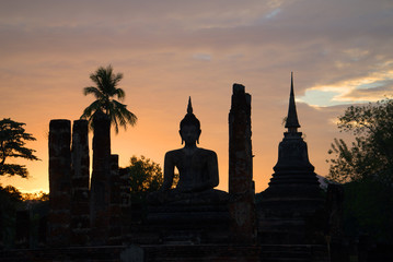 Ancient statue of the sitting Buddha at sunset. Historical park of the city of the Sukhothai, Thailand