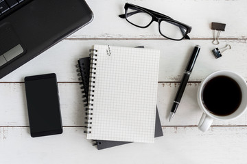 Notebook with laptop and cup of coffee on wooden desk