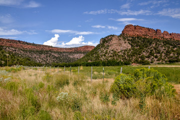 Fototapeta na wymiar red canyon mountains rising over farmlands in the valley Unaweep - Tabeguache scenic byway, Whitewater, Colorado, USA