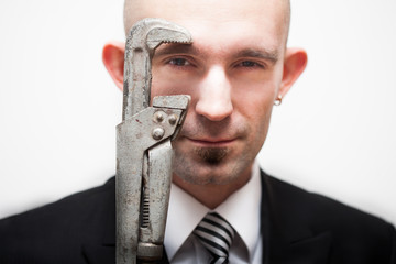 Portrait of man in business suit looking through adjustable wrench on white background