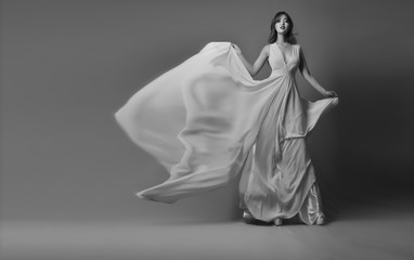 Young model posing in elegant long dress fluttering in the wind