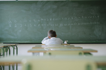 A boy holding head in the classroom