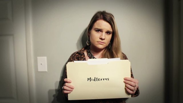Woman holds up manilla folder with her midterms in dramatic lighting