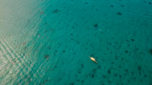 Aerial view of motor boat in sea. Aerial image of motorboat floating in a turquoise blue sea water. Sea landscape with wake of small fast motorboat. Tropical landscape. Philippines, Boracay. 4K video