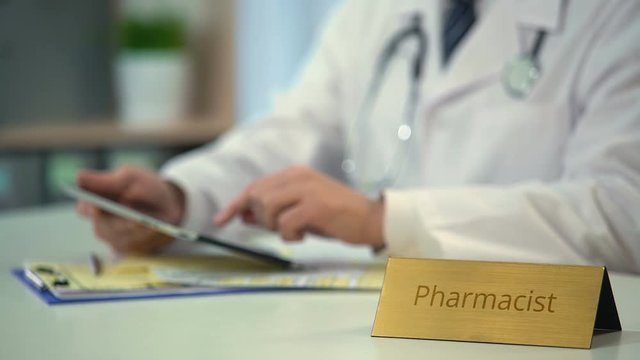 Pharmacist searching name of new drug on tablet, viewing images of medicaments