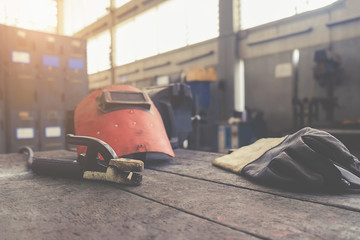 Inverter welding machine, welding equipment on a wooden background, welding mask, leather gloves,...