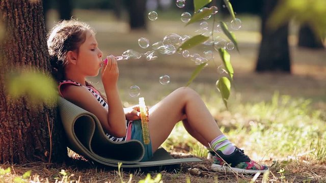 Children girl blowing soap bubbles in outdoor forest