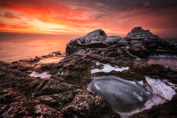 Obraz premium Fire and ice / Rocky beach long exposure winter seascape at sunrise, Bulgaria