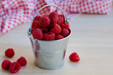 Fresh organic raspberries in metal bucket on wooden background. Healthy eating and vegan concept. Copy space.