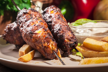 Grilled shish kebab served with fried chips and salad